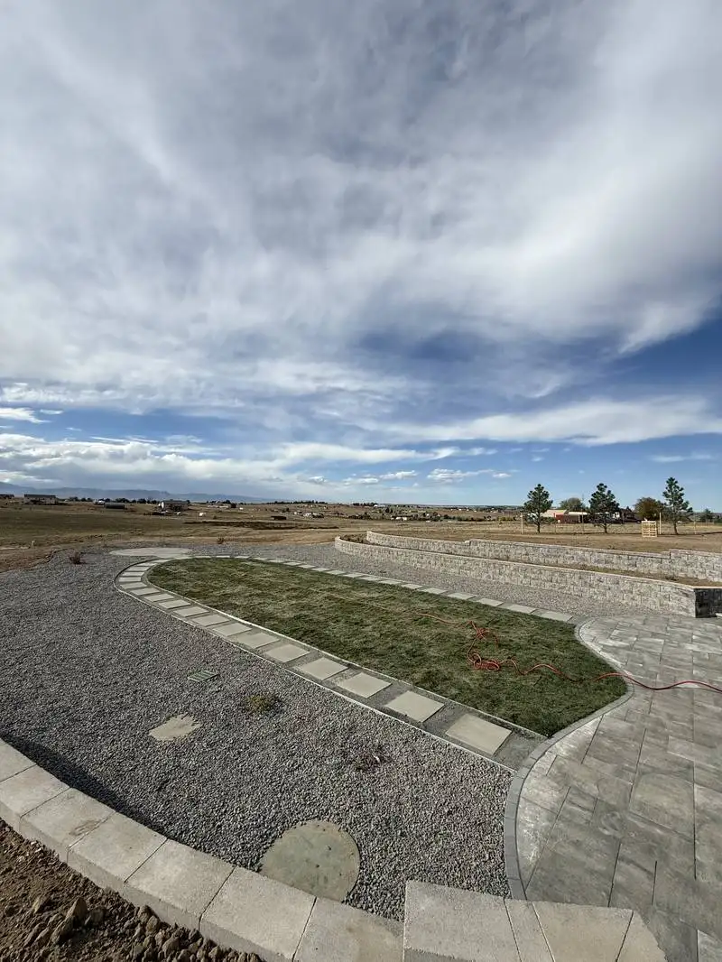 Completed landscape design with paver patio and retaining wall on rural property in Colorado Springs